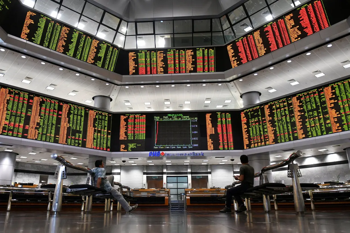 FILE PHOTO: People look at trading boards at a private stock market gallery in Kuala Lumpur