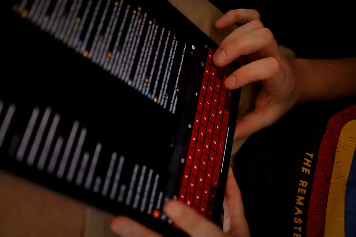 Patrick Kunz uses a tablet while messaging in personal chats in his flat in Regensburg