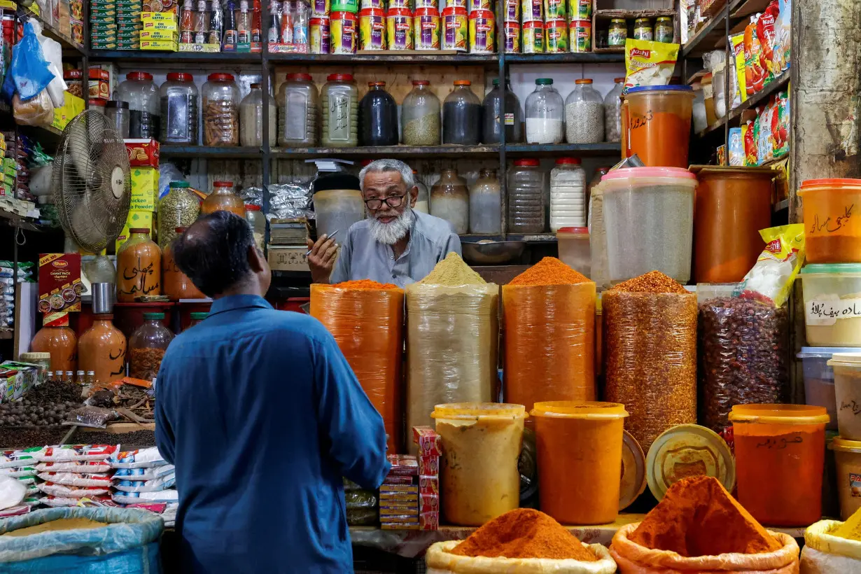 FILE PHOTO: Shopkeeper speaks with a customer while selling spices at a market in Karachi