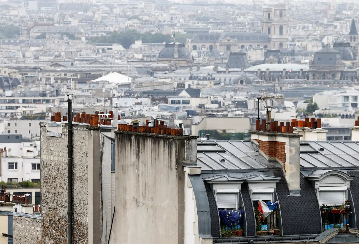 A French flag and a European Union flag hang in the windows overlooking Paris skyline near the Sacre Coeur Basilica in Paris