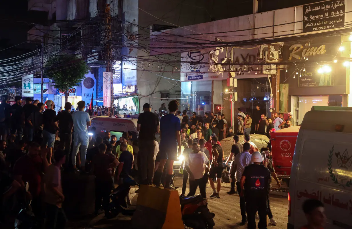 Civil defense members and people gather near a site hit by what security sources said was a strike on Beirut's southern suburbs