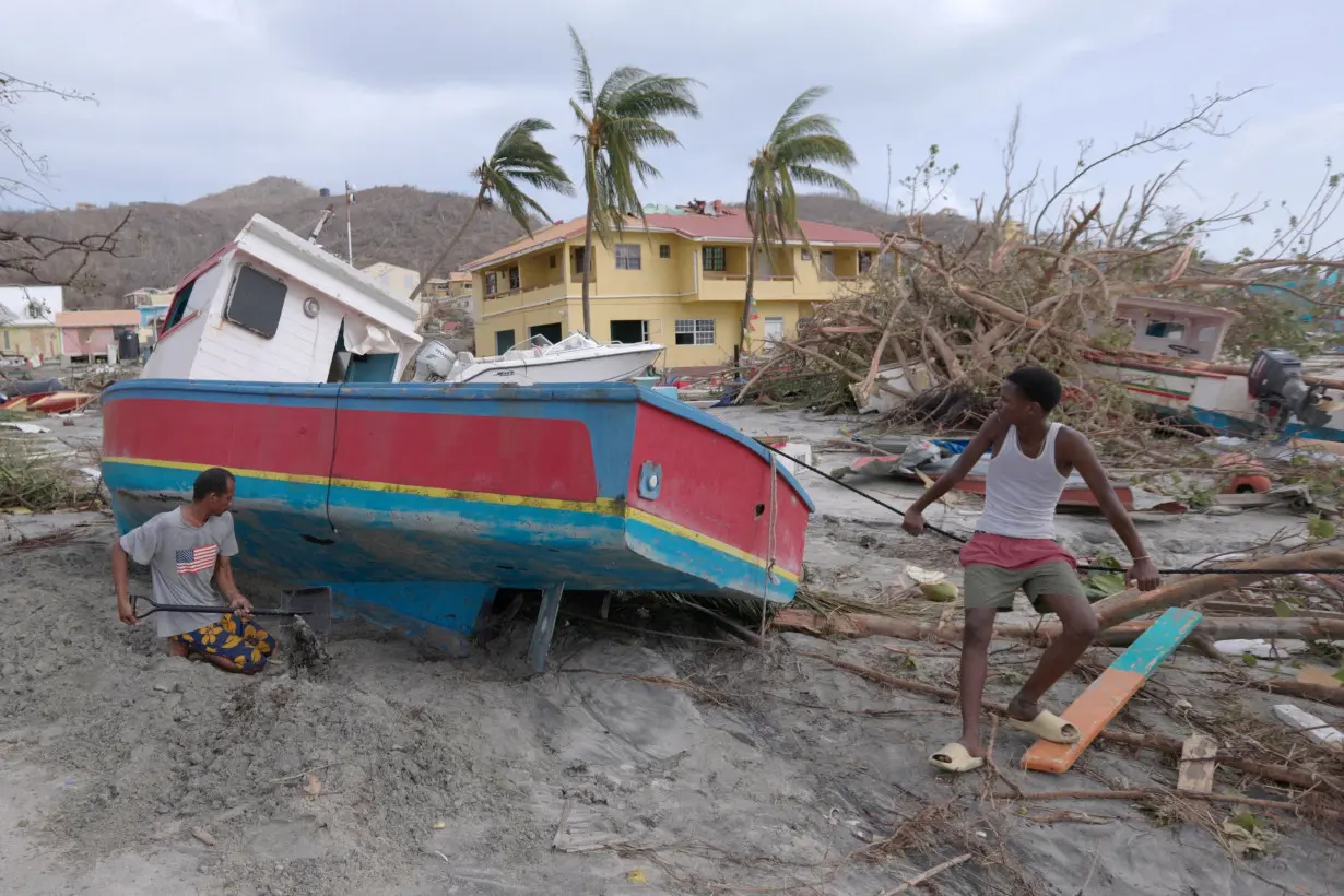 A man digs out a stranded boat after Hurricane Beryl passed the island of Petite Martinique