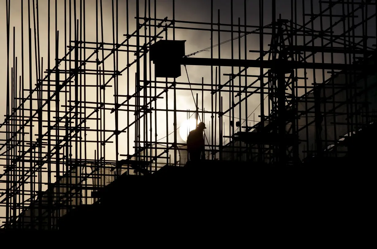 A labourer works during sunrise at a construction site of a residential complex in Puer