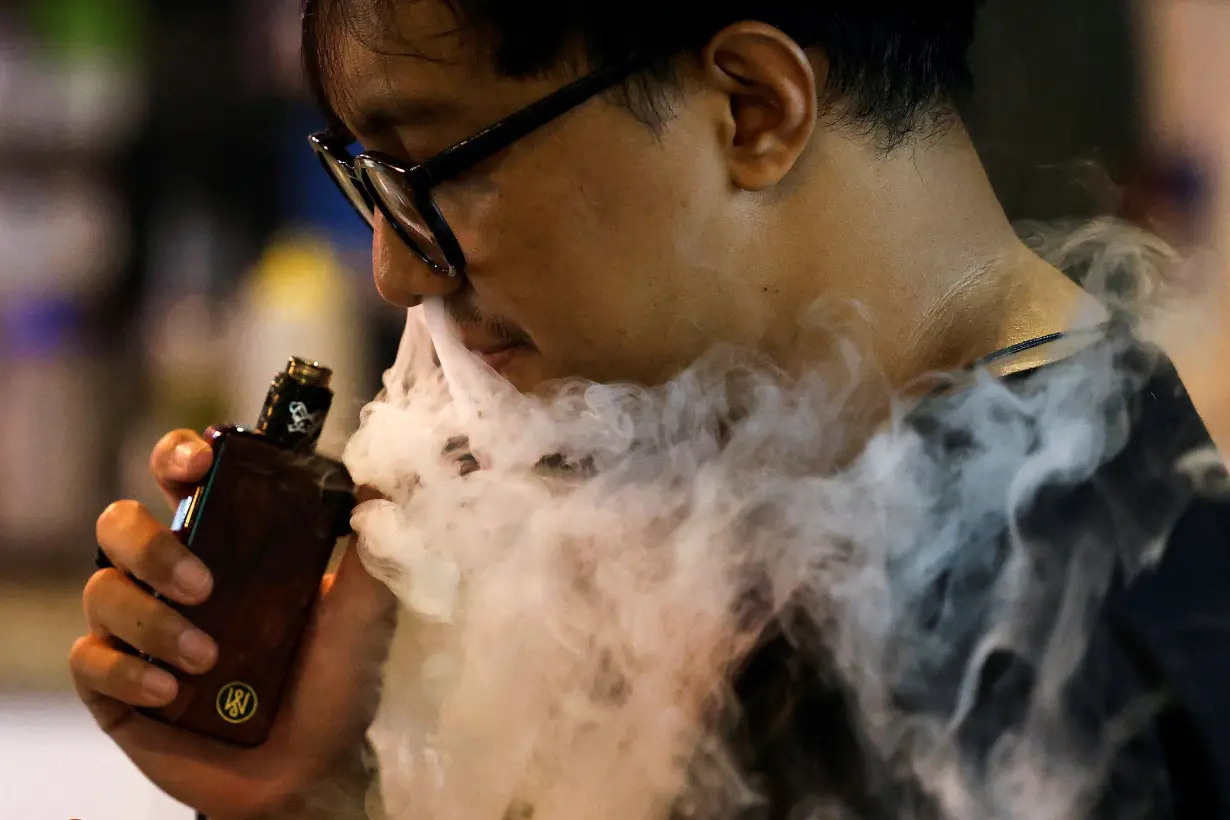 A man vapes at a coffeeshop in Jakarta