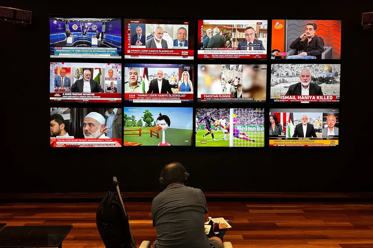 A person watches the news on multiple TV screens, most of them announcing the killing of senior Hamas leader Ismail Haniyeh