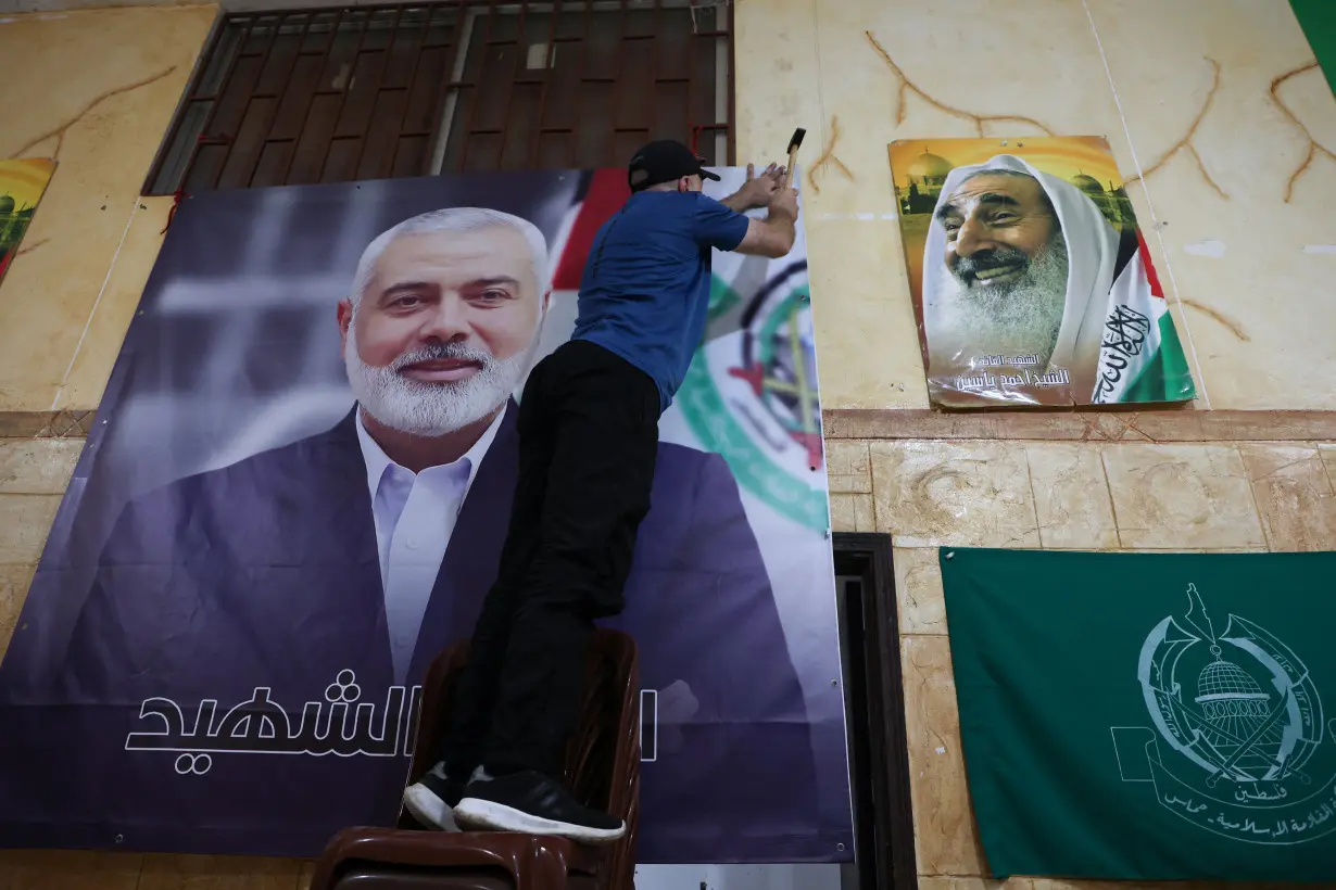 A man hangs a picture of assassinated Hamas leader Haniyeh at Palestinian refugee camp in Beirut