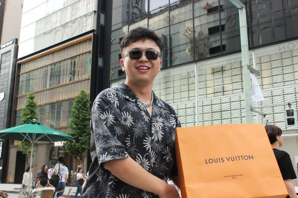 Chinese tourist Zhang Lei poses with a recent purchase in the Ginza shopping district of Tokyo