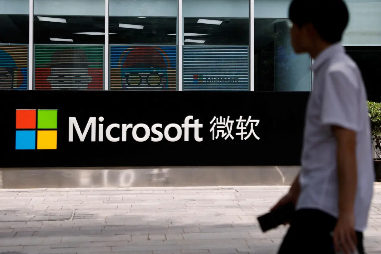 FILE PHOTO: A person walks past a Microsoft sign at its office building in Beijing