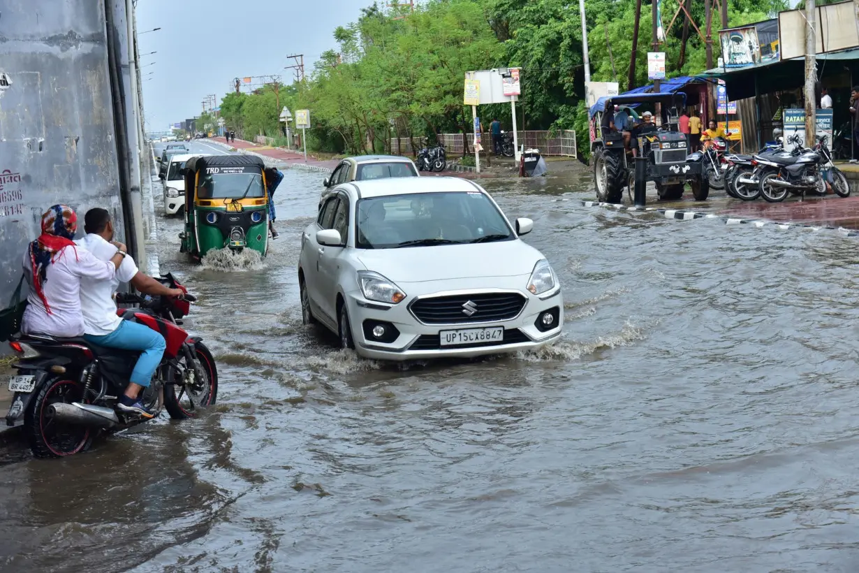 Commuters wade through a waterlogged road during monsoon rainfall at wave city NH9 on June 29 in Ghaziabad, India.