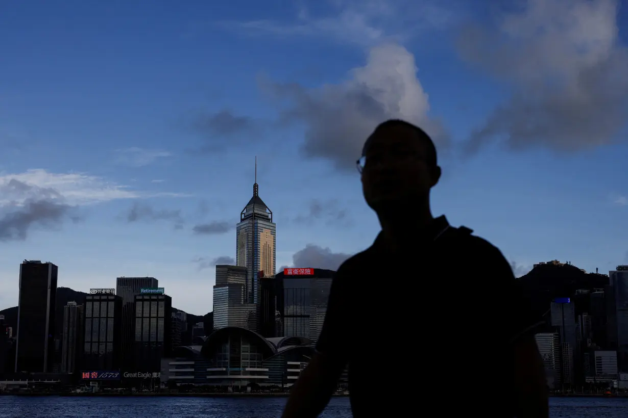 FILE PHOTO: Man walks along the waterfront in front of Victoria Harbour, in Hong Kong