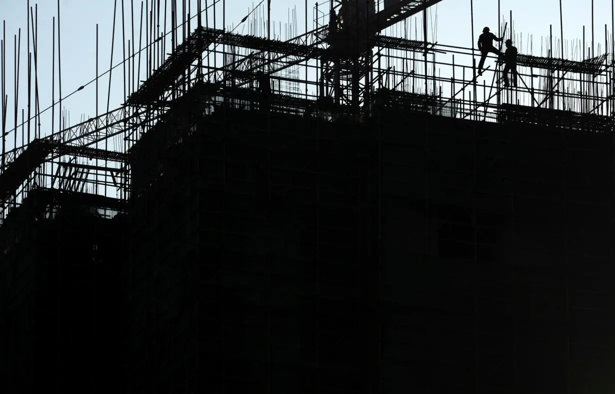 Labourers install scaffolding at a residential construction site in Nanjing