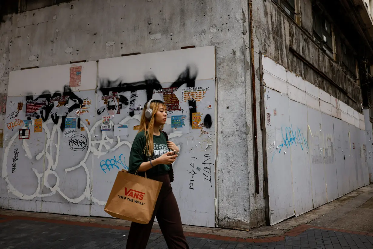 A woman walks past a closed-down retail shop in Tsim Sha Tsui, Hong Kong