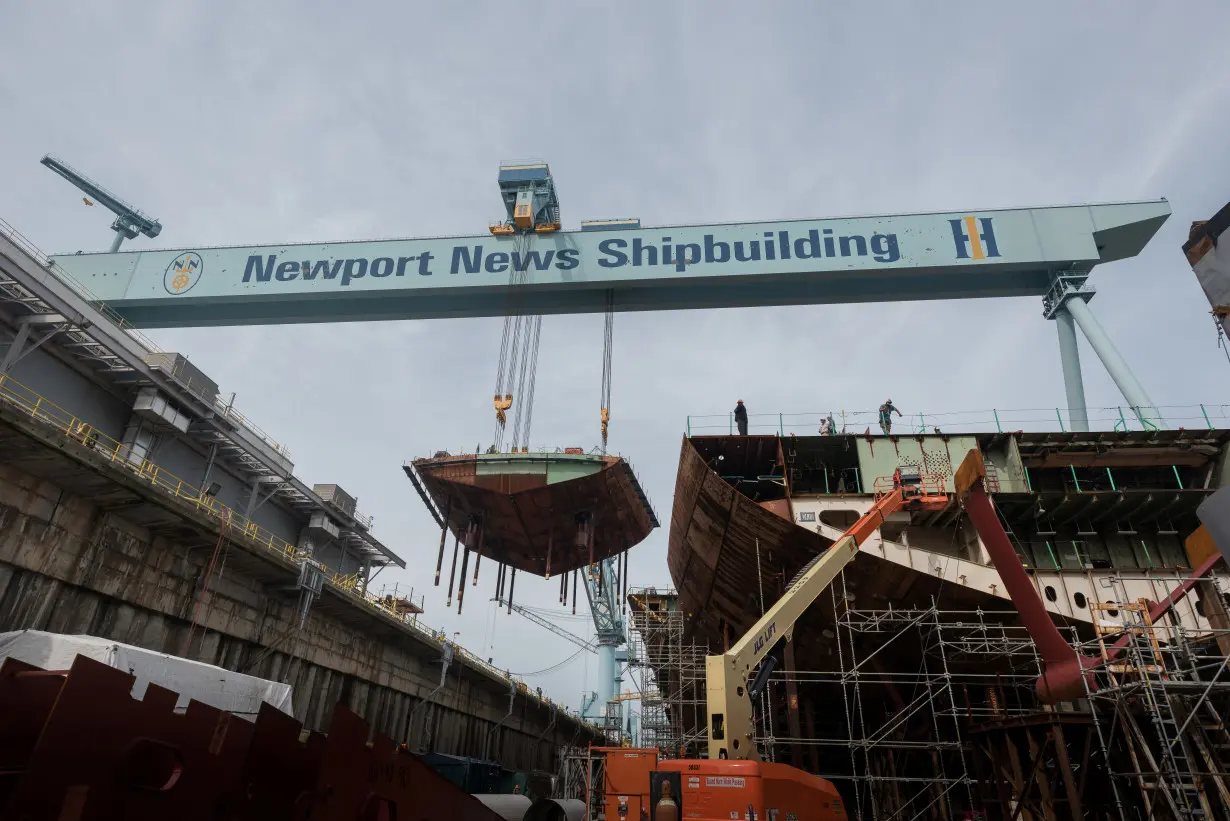 A crane moves the lower stern into place on the nuclear-powered aircraft carrier USS John F. Kennedy (CVN 79) at Huntington Ingalls Shipbuilding in Newport News