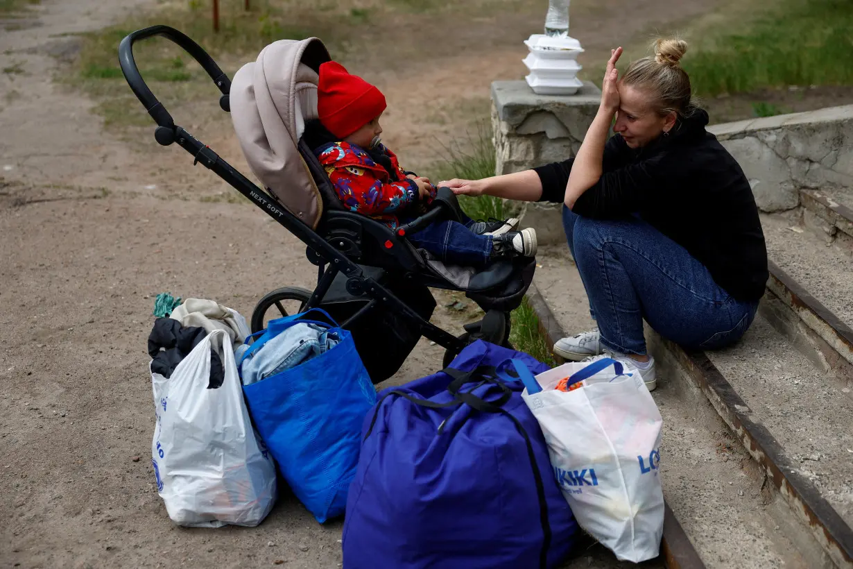 Iryna from the Prykolotne village cries while she waits with her 1-year-old son Mikhailo for an evacuation bus to Kharkiv due to Russian shelling near a border in Kharkiv region