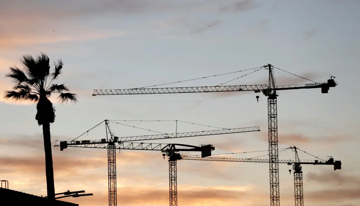 Construction cranes are pictured at sunset in Los Angeles