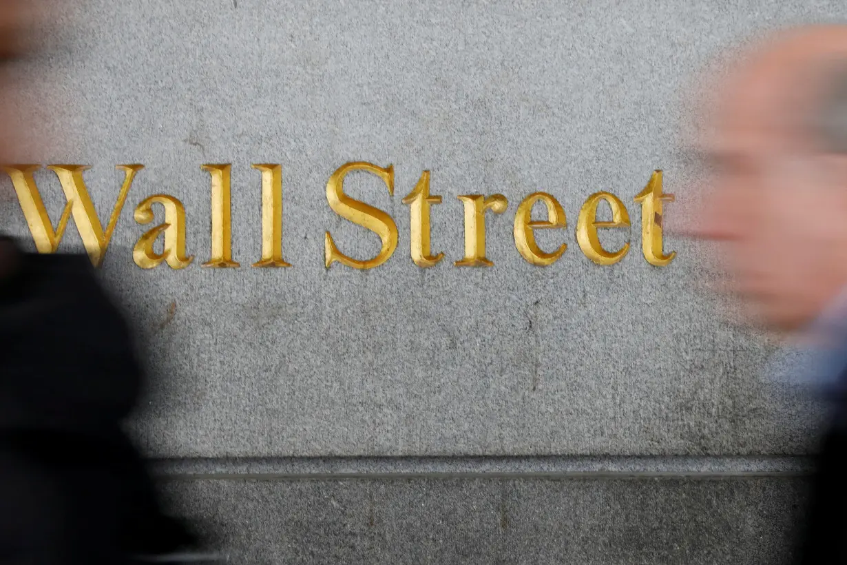 FILE PHOTO: People walk by a Wall Street sign close to the NYSE in New York