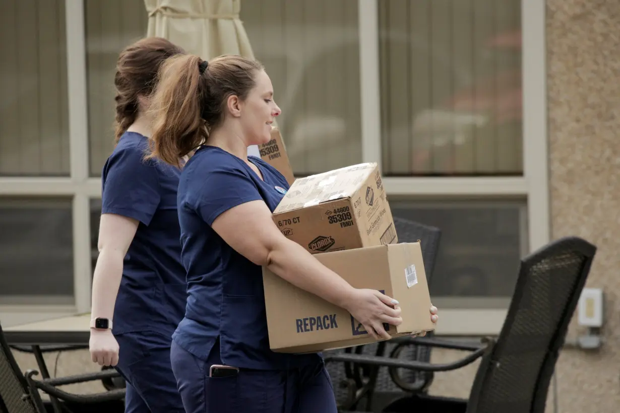 Healthcare workers carry Clorox wipes and other supplies into the Life Care Center of Kirkland, the long-term care facility linked to several confirmed coronavirus cases in the state, in Kirkland