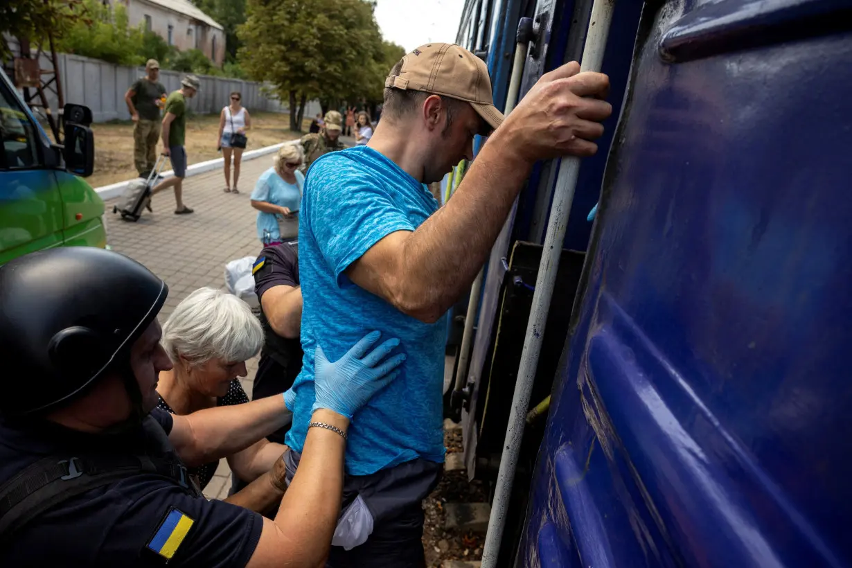 Volunteers of East SOS assist a man to enter an evacuation train, as Russian forces advance across the frontlines in the Donetsk region, at the train station in Pokrovsk