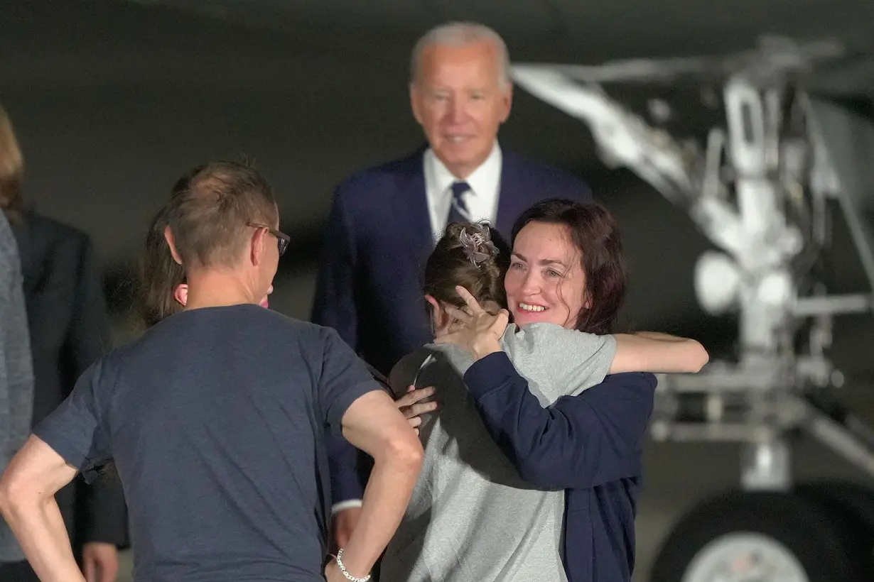 President Joe Biden looks on as Alsu Kurmasheva hugs family on the tarmac after arriving at Andrews Air Force Base, Maryland, August 1, 2024.