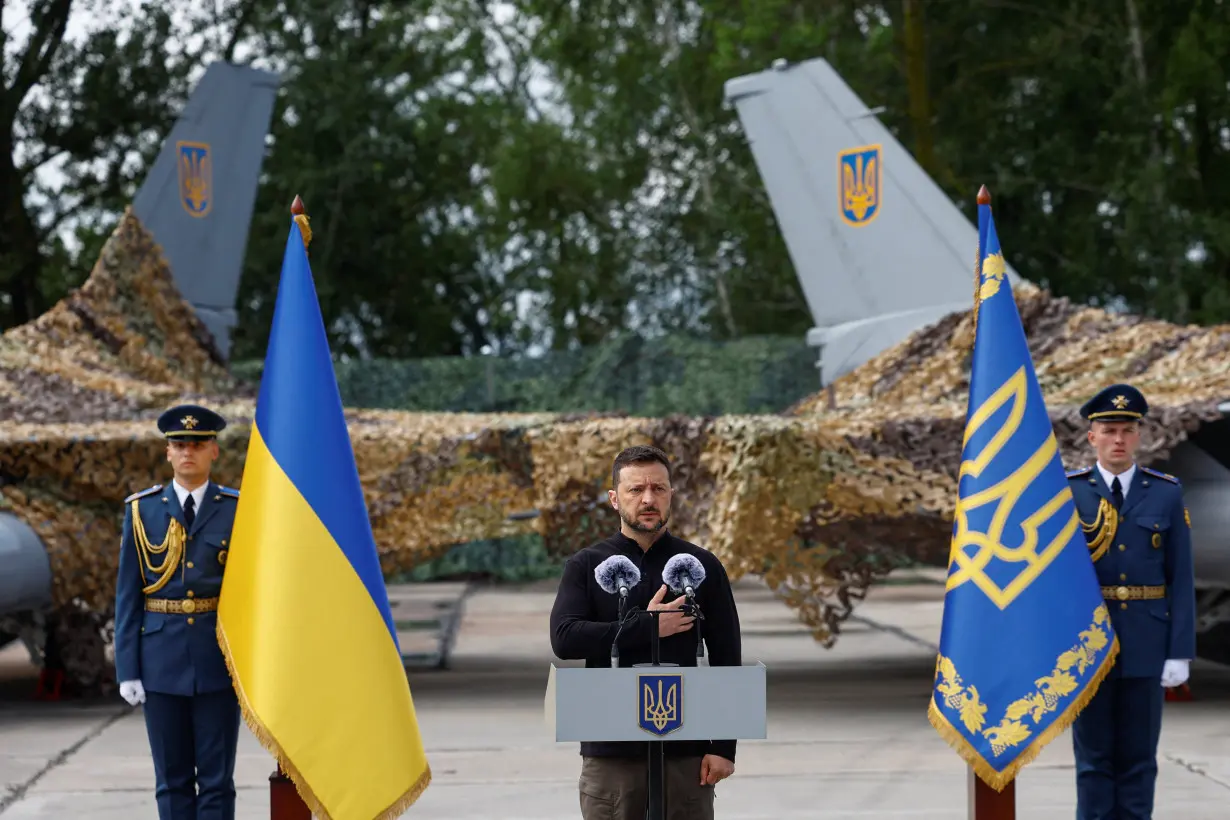 Ukraine's President Zelenskiy signs a national anthem next to F-16 fighting aircrafts during marking the Day of the Ukrainian Air Forces in an undisclosed location in Ukraine