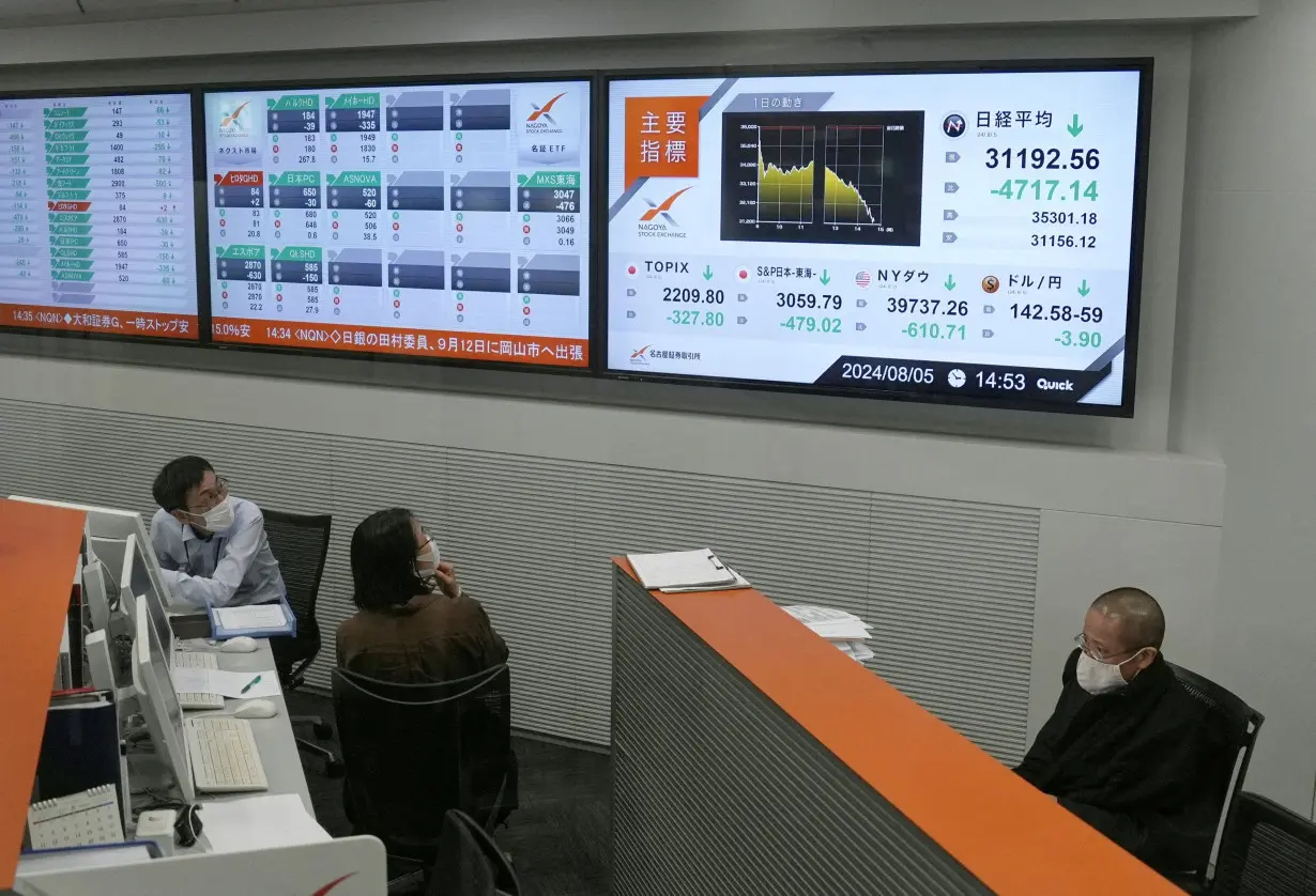 Employees look on the monitors displaying Japan's Nikkei share average, which has had a record breaking-drop in the closing price, at Nagoya Stock Exchange in Nagoya