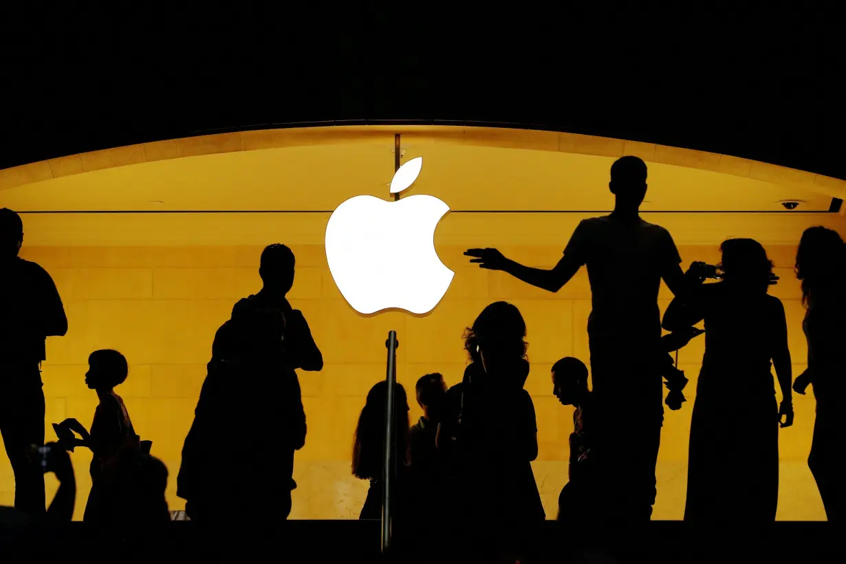 FILE PHOTO: Customers walk past an Apple logo inside of an Apple store at Grand Central Station in New York