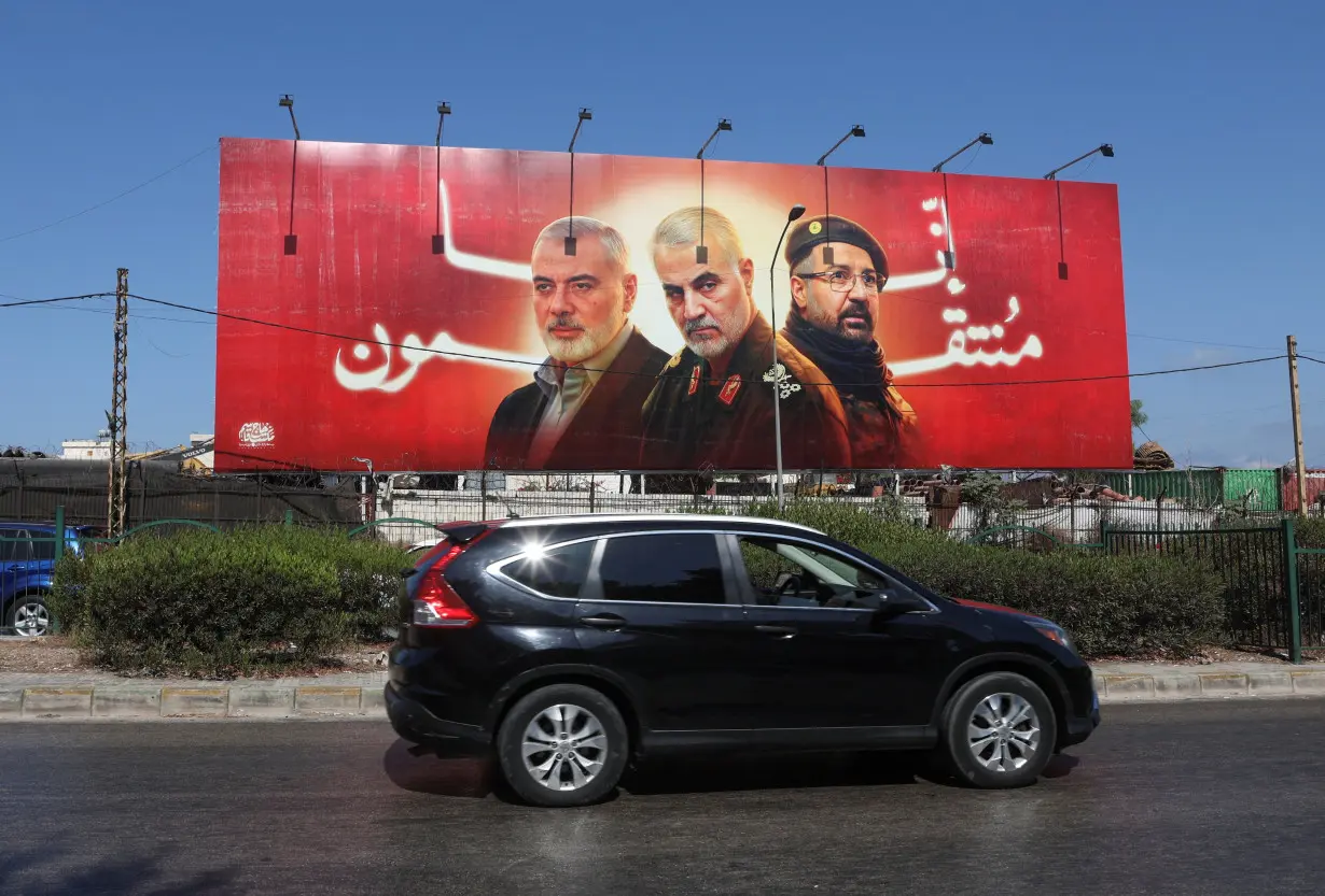 A car drives past a poster depicting late Hamas leader Ismail Haniyeh, top commander of Iran's Quds Force Qassem Soleimani and Hezbollah top commander Fuad Shukr in Beirut