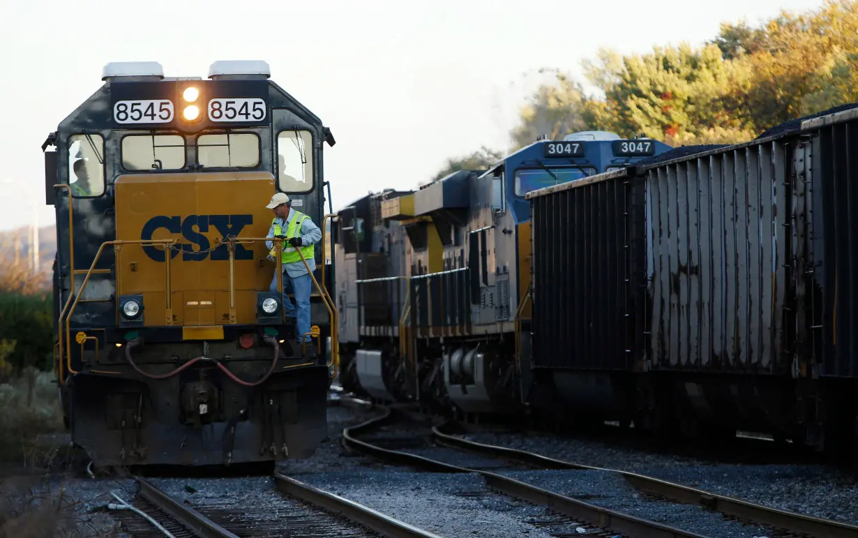 A CSX coal train moves past an idling CSX engine at the switchyard in Brunswick, Maryland