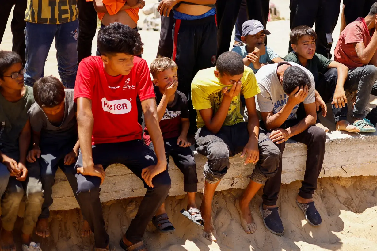 People bury the bodies of unidentified Palestinians at a mass grave after the bodies were handed over by Israel, in Khan Younis