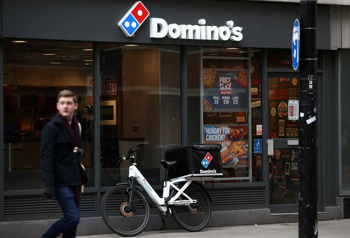 FILE PHOTO: A person walks past a Domino's pizza restuarant in London