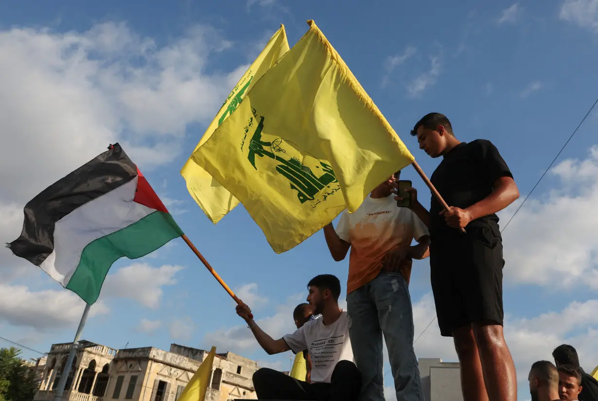 Demonstrators hold Hezbollah and Palestinian flags during in a protest condemning the killing of Hamas chief Ismail Haniyeh, in Sidon