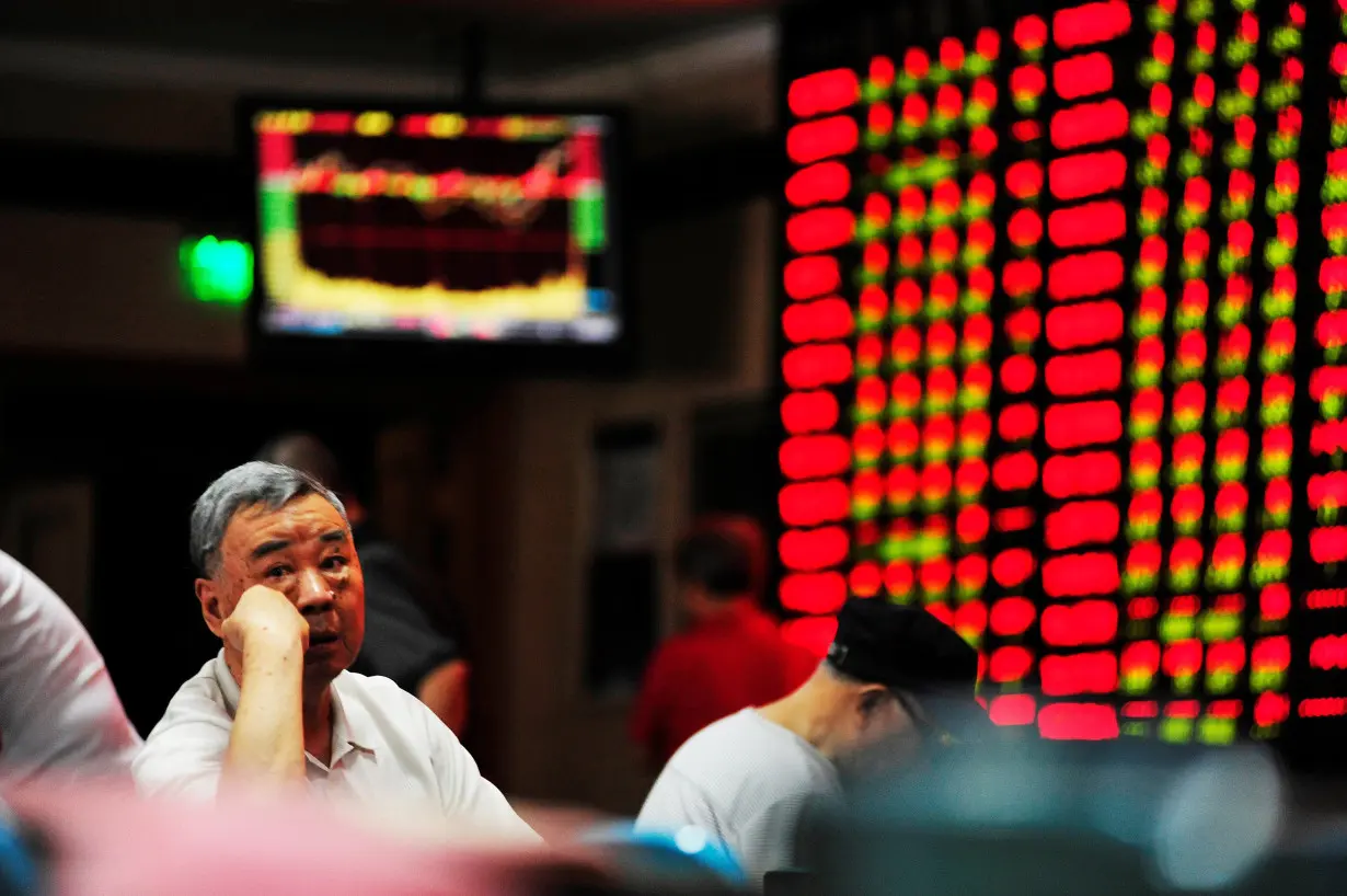 An investor sits in front of an electronic board showing stock information at a brokerage house in Nanjing