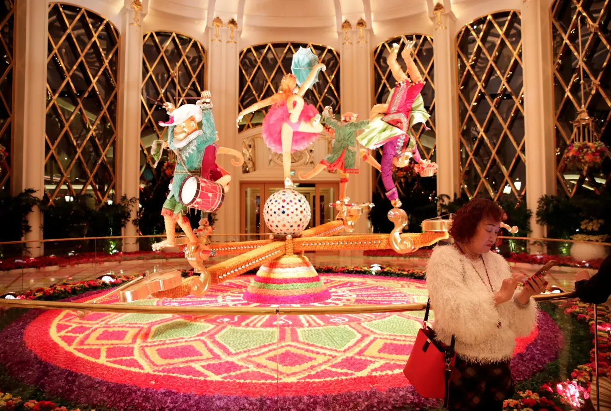 A woman rest next to the decoration inside the Wynn Palace casino resort in Macau