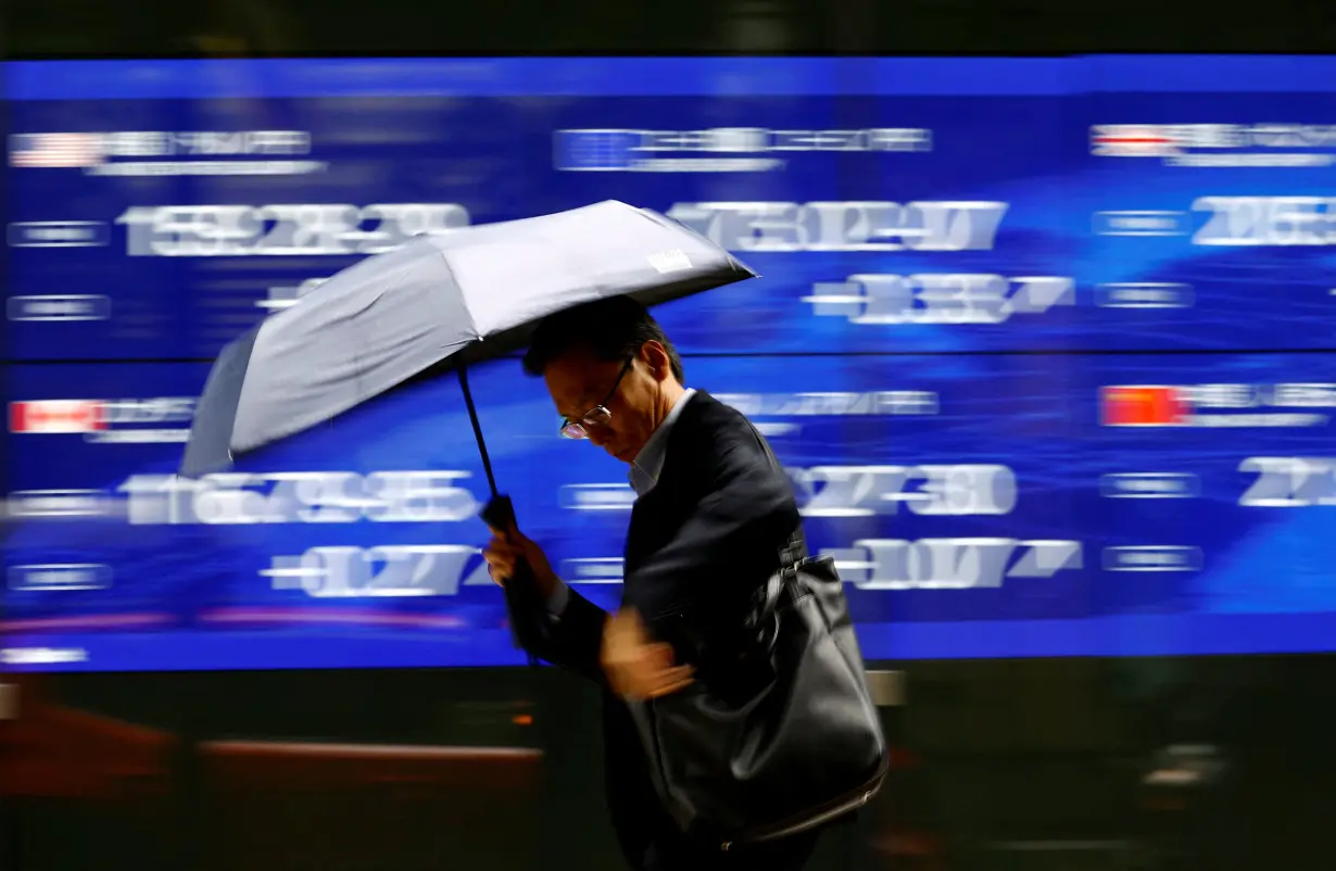 A man walks past an electronic screen displaying the current Japanese Yen exchange rate against the U.S. dollar, Euro and other foreign currencies in Tokyo