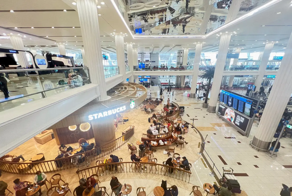 FILE PHOTO: People sit at a coffee shop as they wait for their flight after a rainstorm hits Dubai, causing delays at the Dubai International Airport