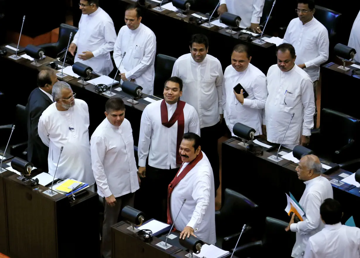 Sri Lanka's newly appointed Prime Minister Rajapaksa and his son Namal look on before they leave the parliament in Colombo