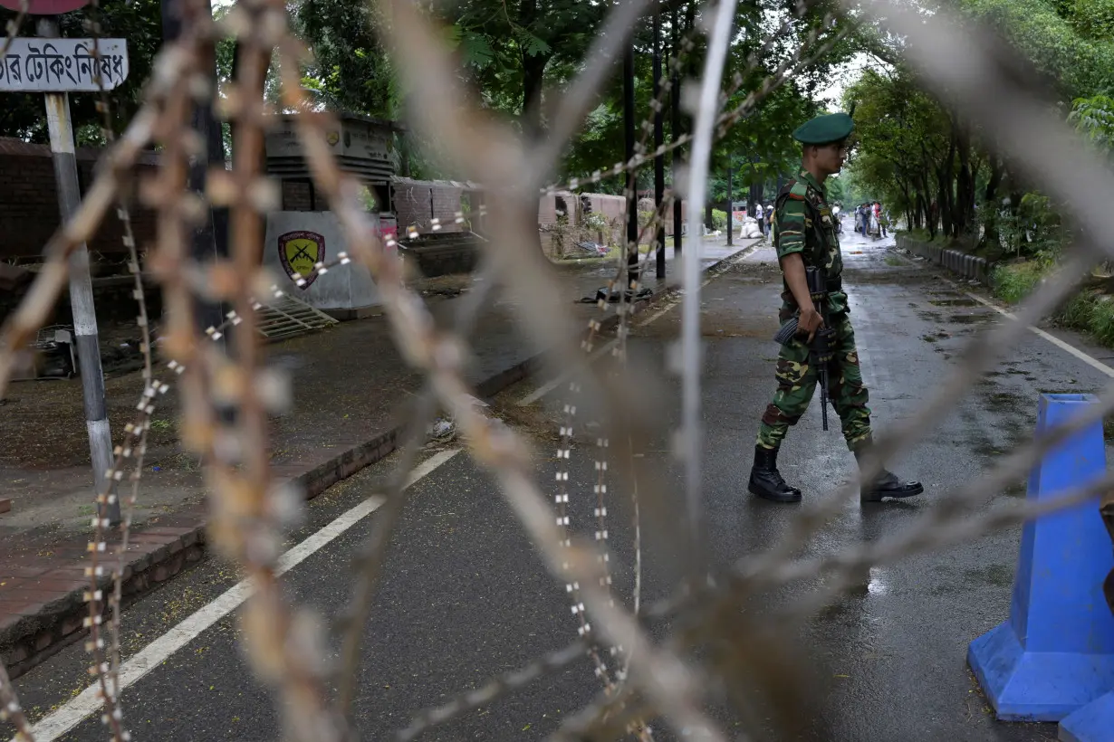 FILE PHOTO: A security force personnel walks behind concertina wire placed across a road next to the residence of Sheikh Hasina, in Dhaka