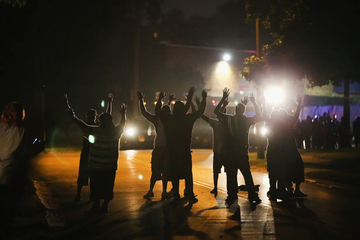 With their hands raised, residents gather at a police line as the neighborhood is locked down following skirmishes on August 11, 2014 in Ferguson, Missouri.