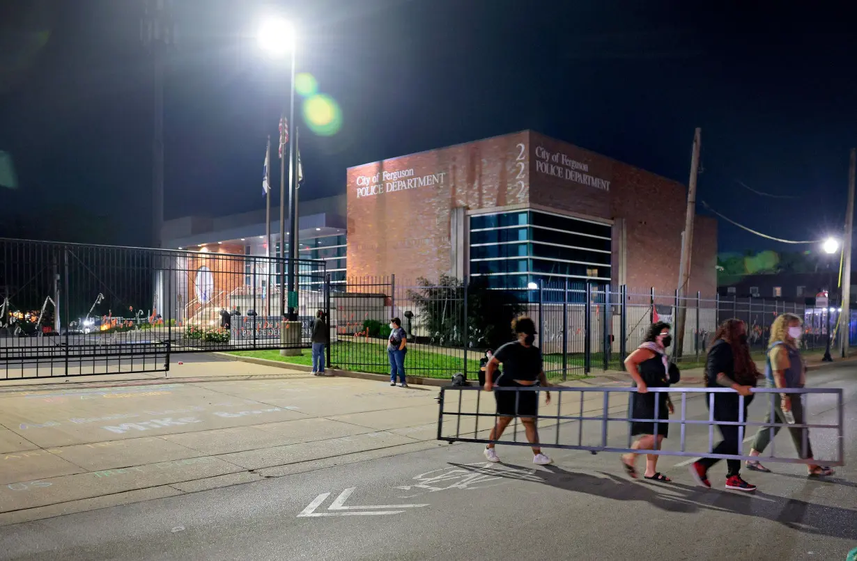 Protesters dismantle and remove a portion of a newly-installed gate outside the Ferguson, Missouri, police station on August 9, before their actions prompted arrests.