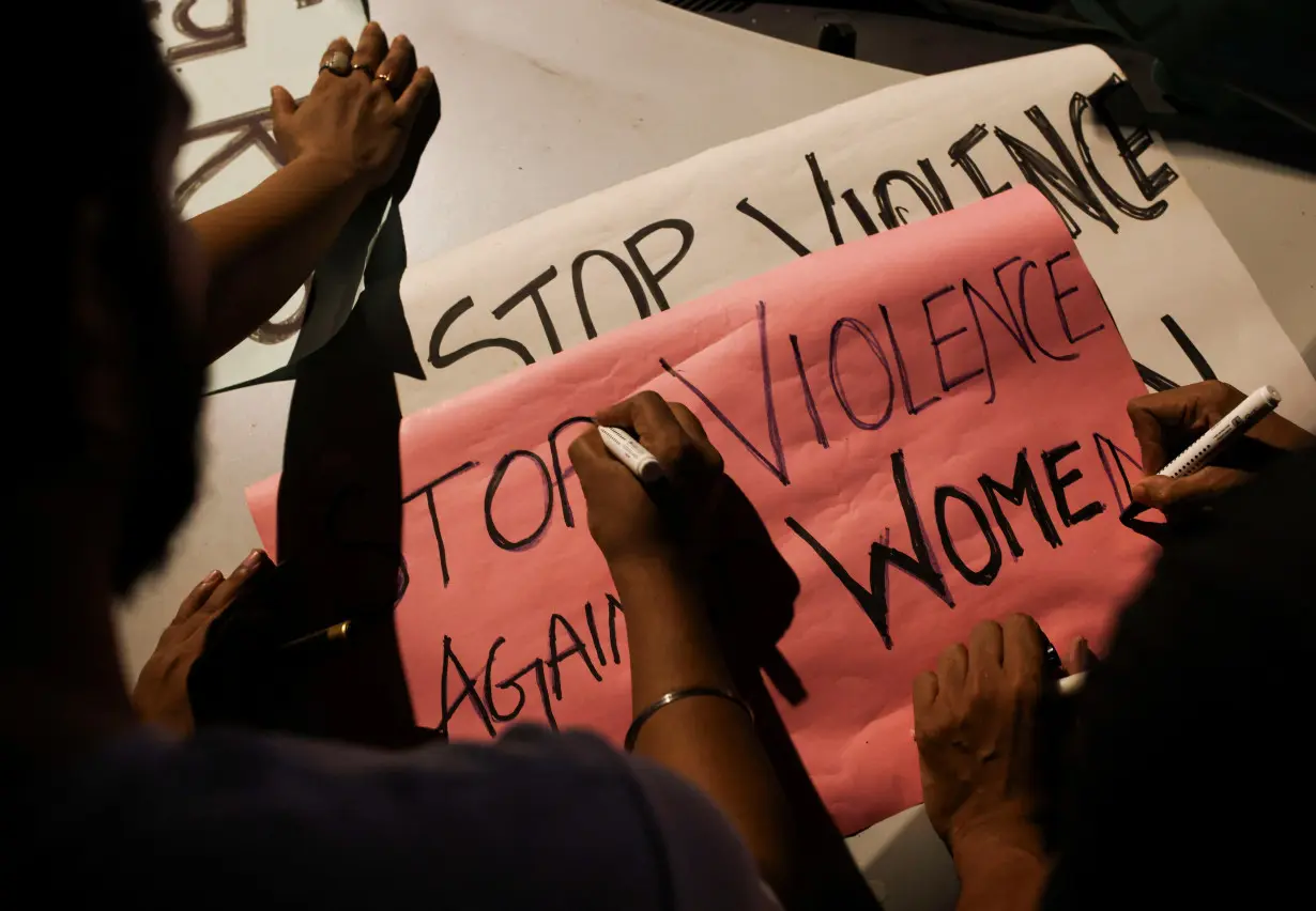 People write slogans on posters before the start of a candlelight vigil condemning the rape and murder of a trainee medic at a government-run hospital in Kolkata, on a street in Mumbai