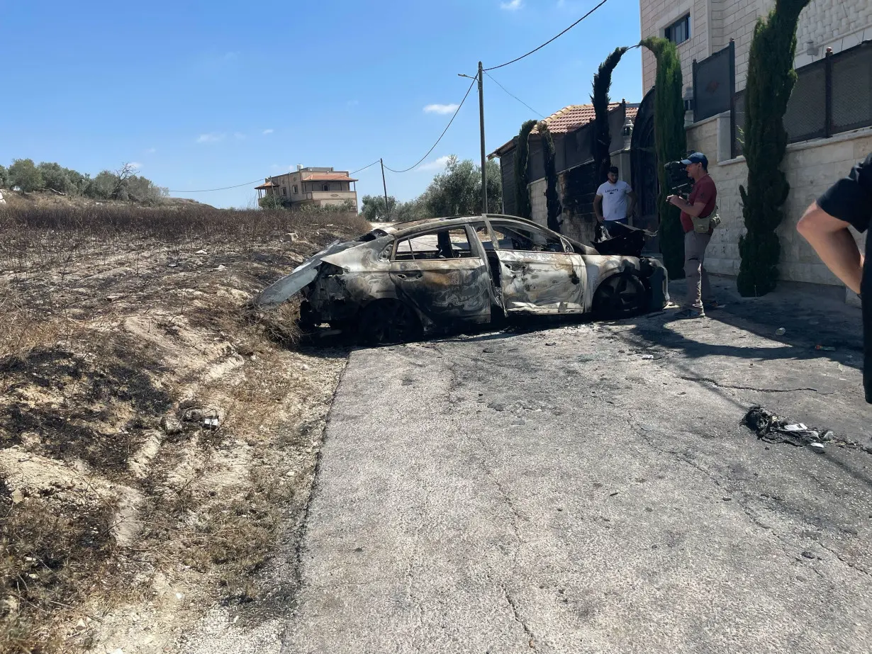 A car of a resident is damaged after being torched during a deadly settler attack on Thursday, in the West Bank town of Jit.