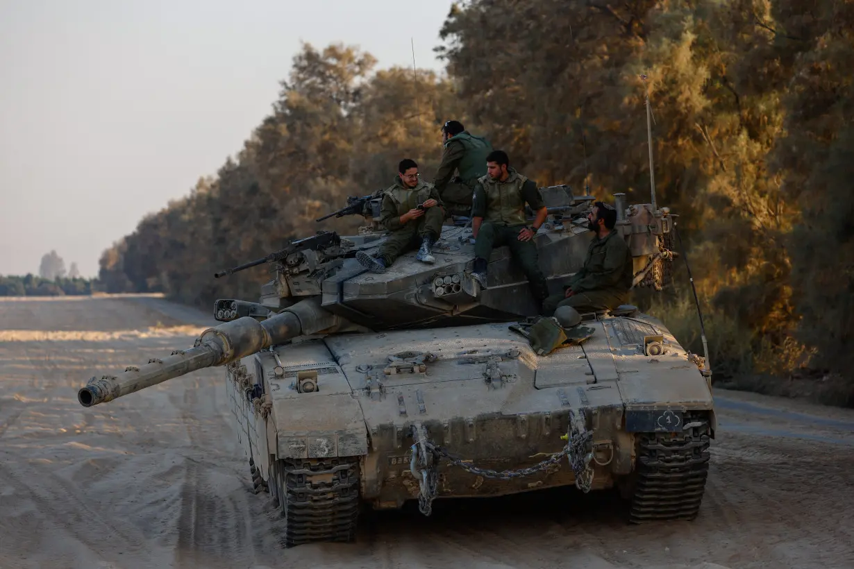 Israeli soldiers rest on top of their tank near the Israel-Gaza border