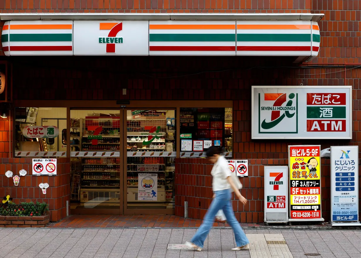 A pedestrian walks past Japan's Seven & I's 7-Eleven convenience store in Tokyo