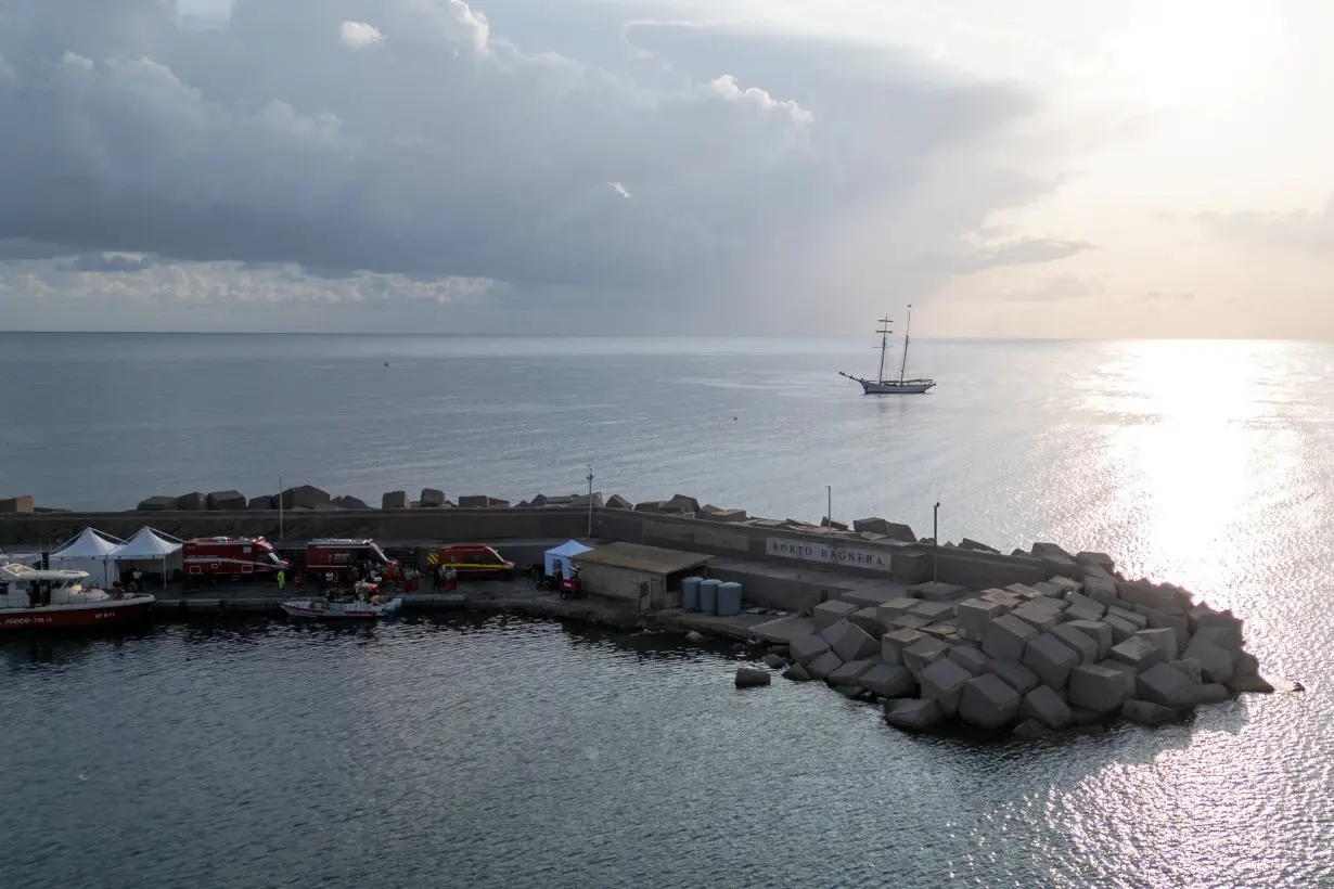 Rescue service vehicles and personnel at a port near the site where a luxury yacht sank, in Porticello