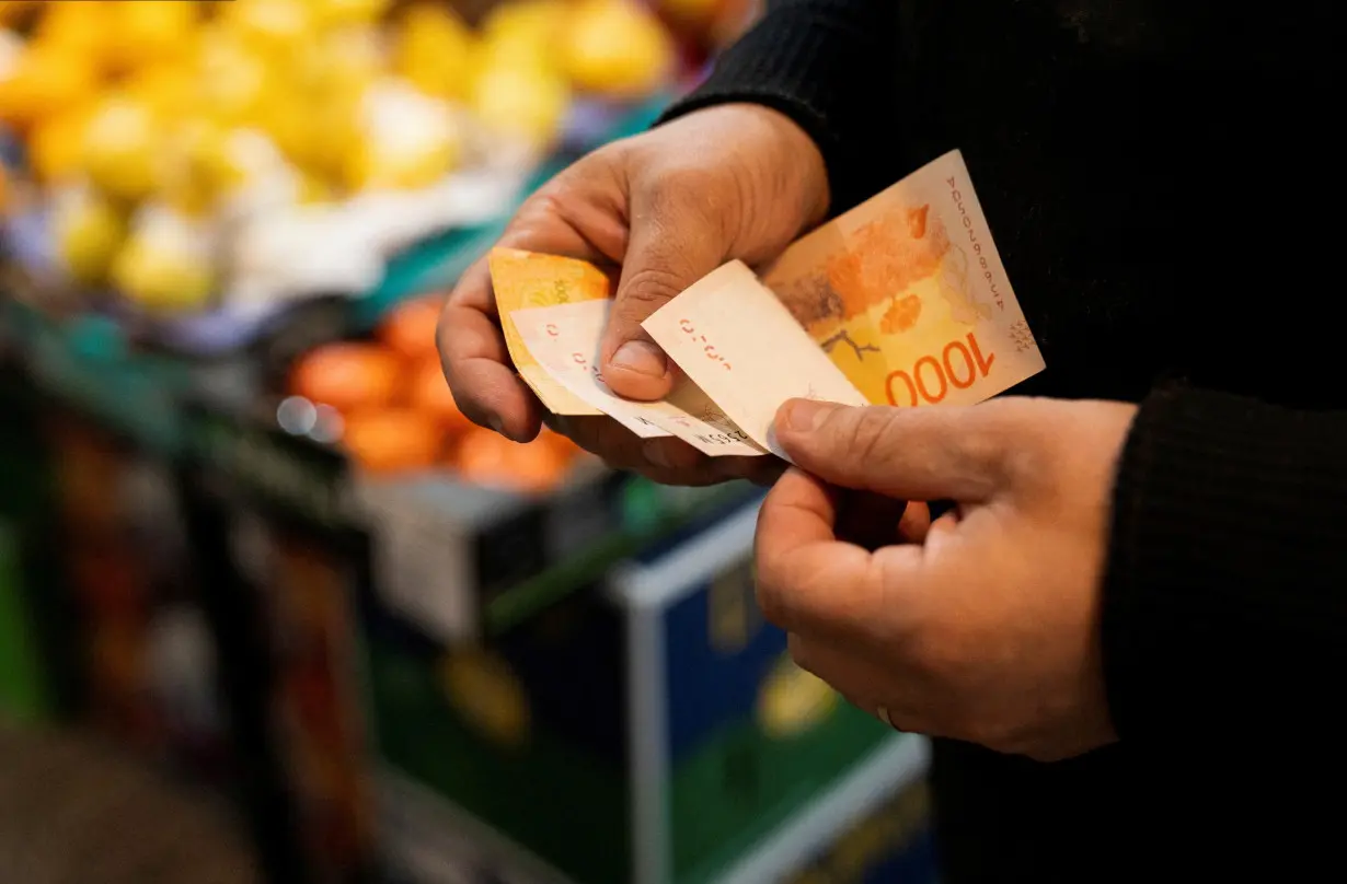 FILE PHOTO: A greengrocer counts Argentine peso bills at a local market,as Argentina is due to release consumer inflation data for April, in Buenos Aires