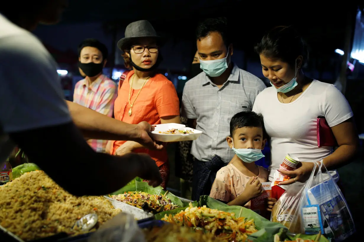 A family wearing protective masks purchases food at a market in Yangon