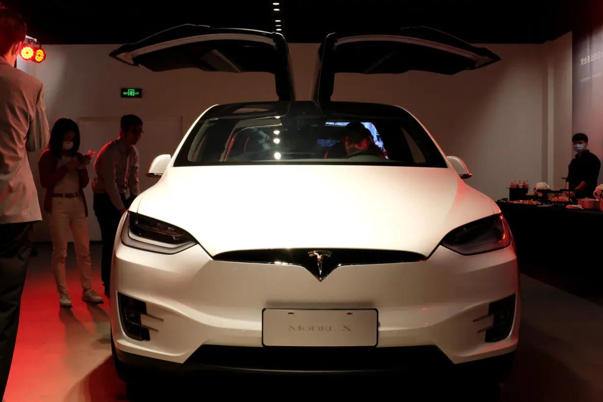 People check a Tesla Model X sport utility vehicle at a new Tesla showroom in Shanghai