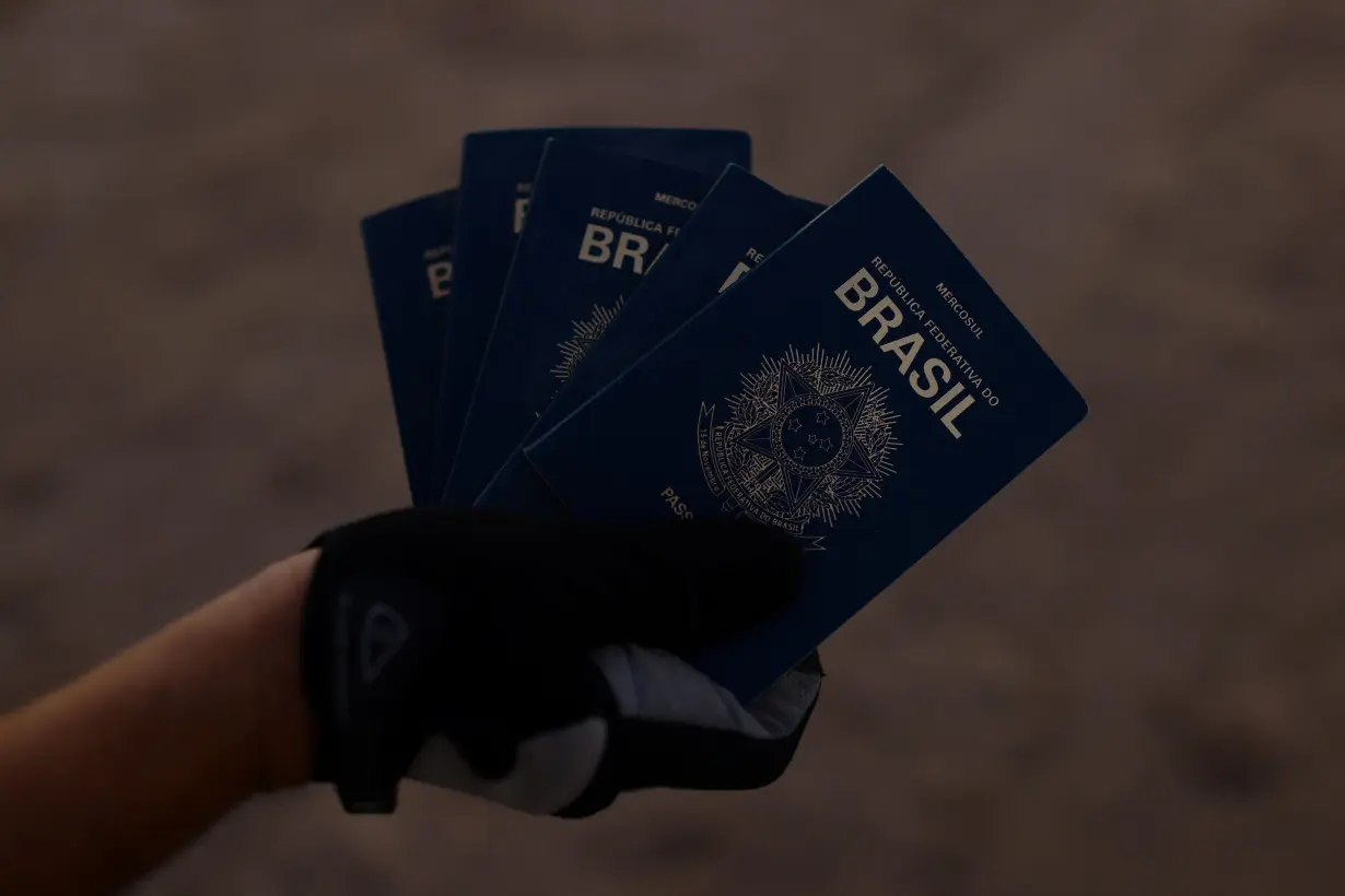 A person shows passports from Brazil that were found on the banks of the Rio Bravo River,in Ciudad Juarez