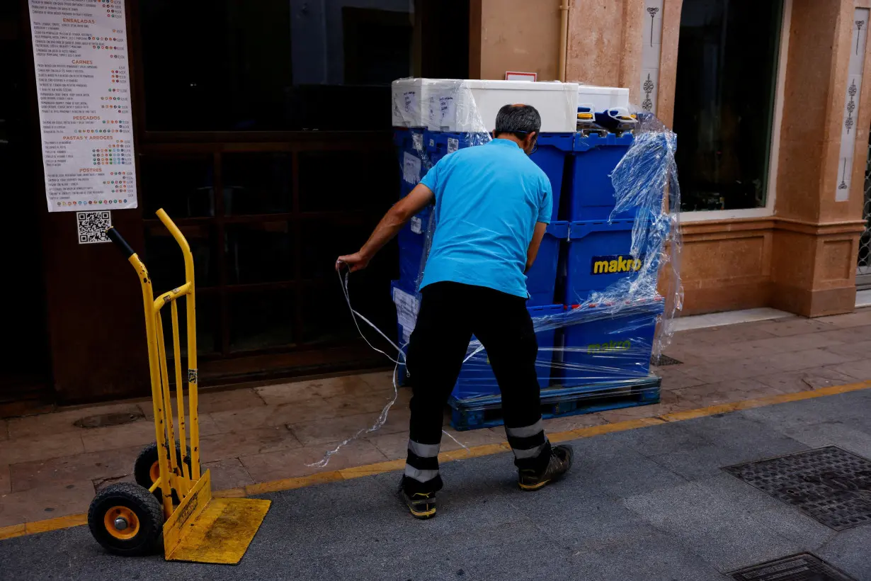 FILE PHOTO: A delivery worker unpacks boxes outside a restaurant in Ronda, Spain