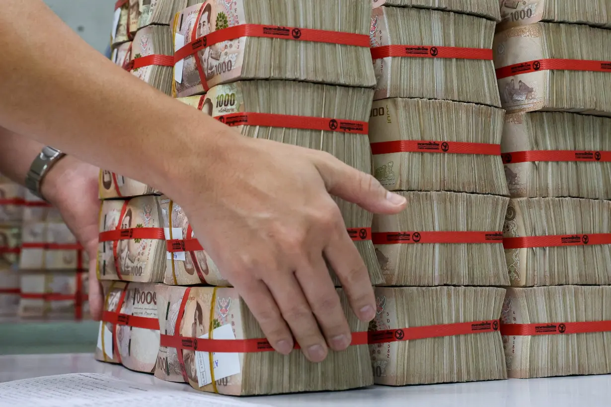 A bank employee gathers Thai baht notes at a Kasikornbank in Bangkok